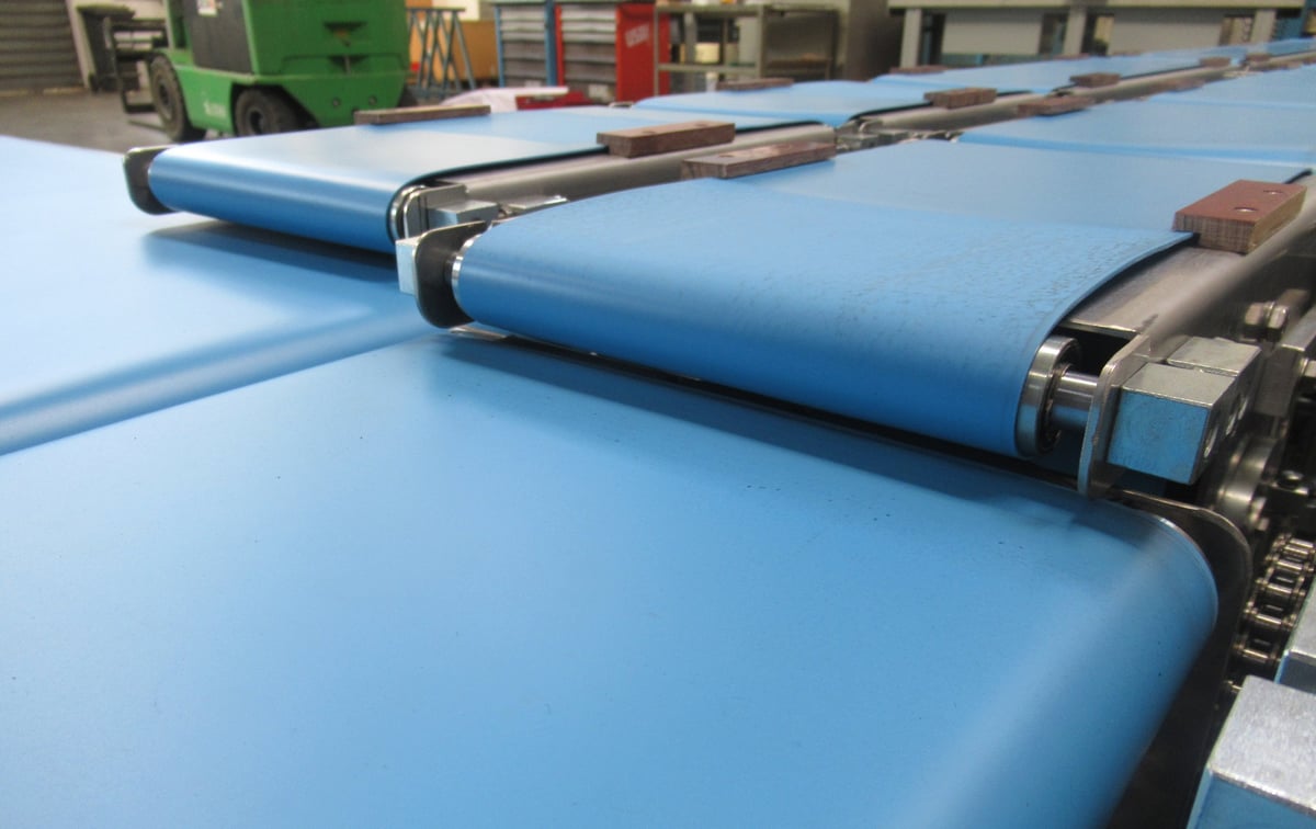 Dettaglio di rulli industriali con materiale azzurro in lavorazione